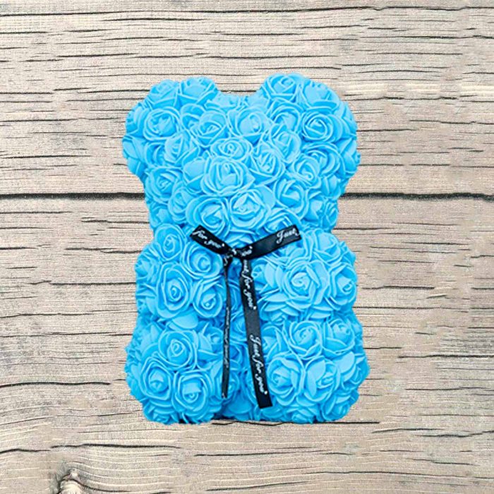 Ourson mousse en roses bleues artificielles dans sa boite.